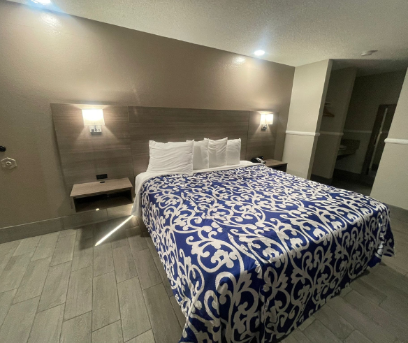 A cozy hotel room featuring a bed adorned with a blue blanket, ideal for budget travelers and extended stays.