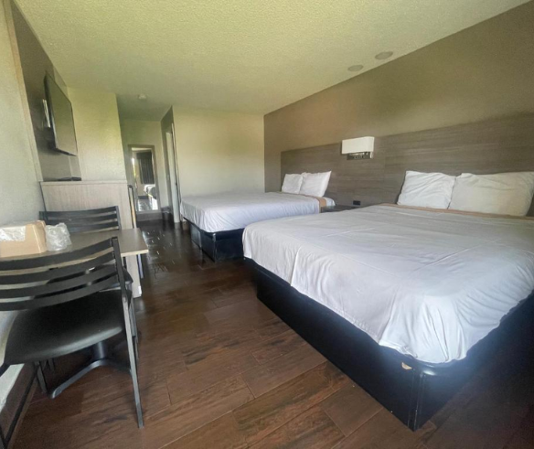 Two beds in a hotel room featuring a television, ideal for budget travelers and extended stays at Simple Stay Suites.