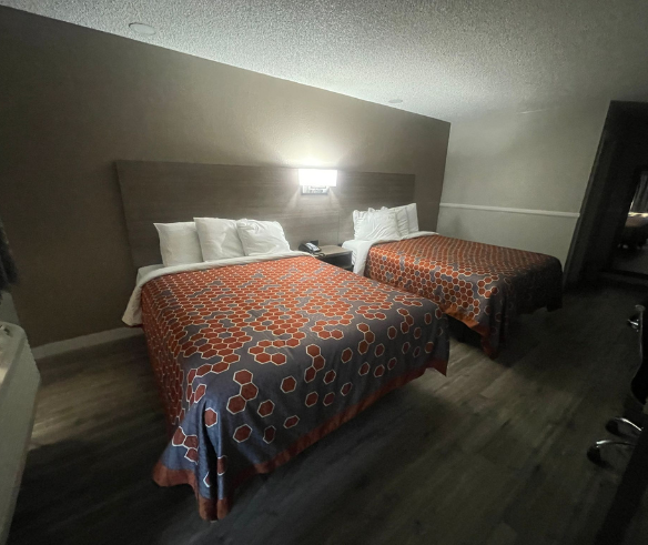 A hotel room featuring two beds with vibrant orange and blue blankets, perfect for affordable lodging at Simple Stay Suites.